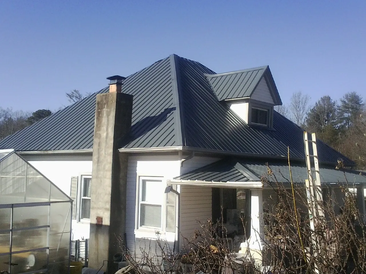 Dark blue standing seam metal roof on a white farmhouse with dormer — Slate & Tile Roof Repair by Roofing Brothers in Candler