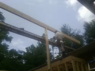 Carpenter setting a ridge beam over a new addition frame — Ice Dam Removal by Roofing Brothers in Candler