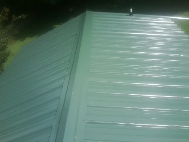 New green metal panels meeting at the ridge of a roof — Flat Roof Repair work by our crew in Candler