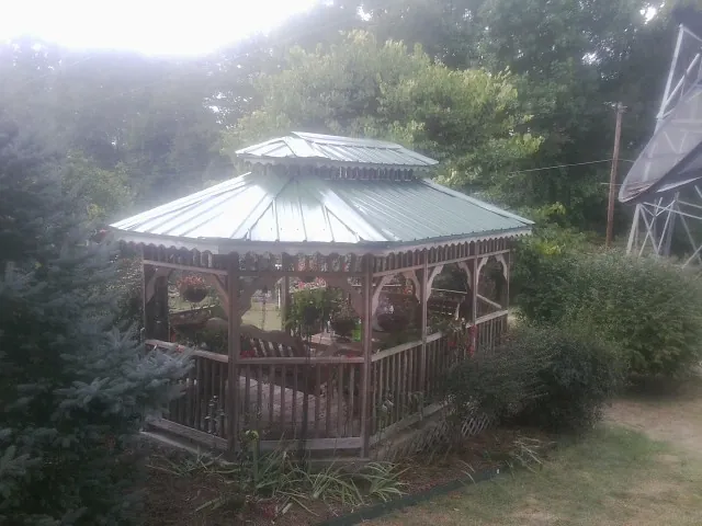 Green metal roof on a backyard gazebo surrounded by garden beds in Candler