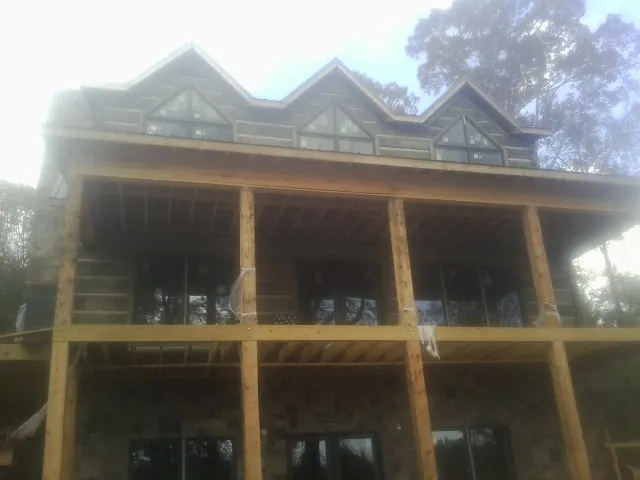 Dormers and porch framing on a large log home under construction — Roof Coating work by our crew in Candler