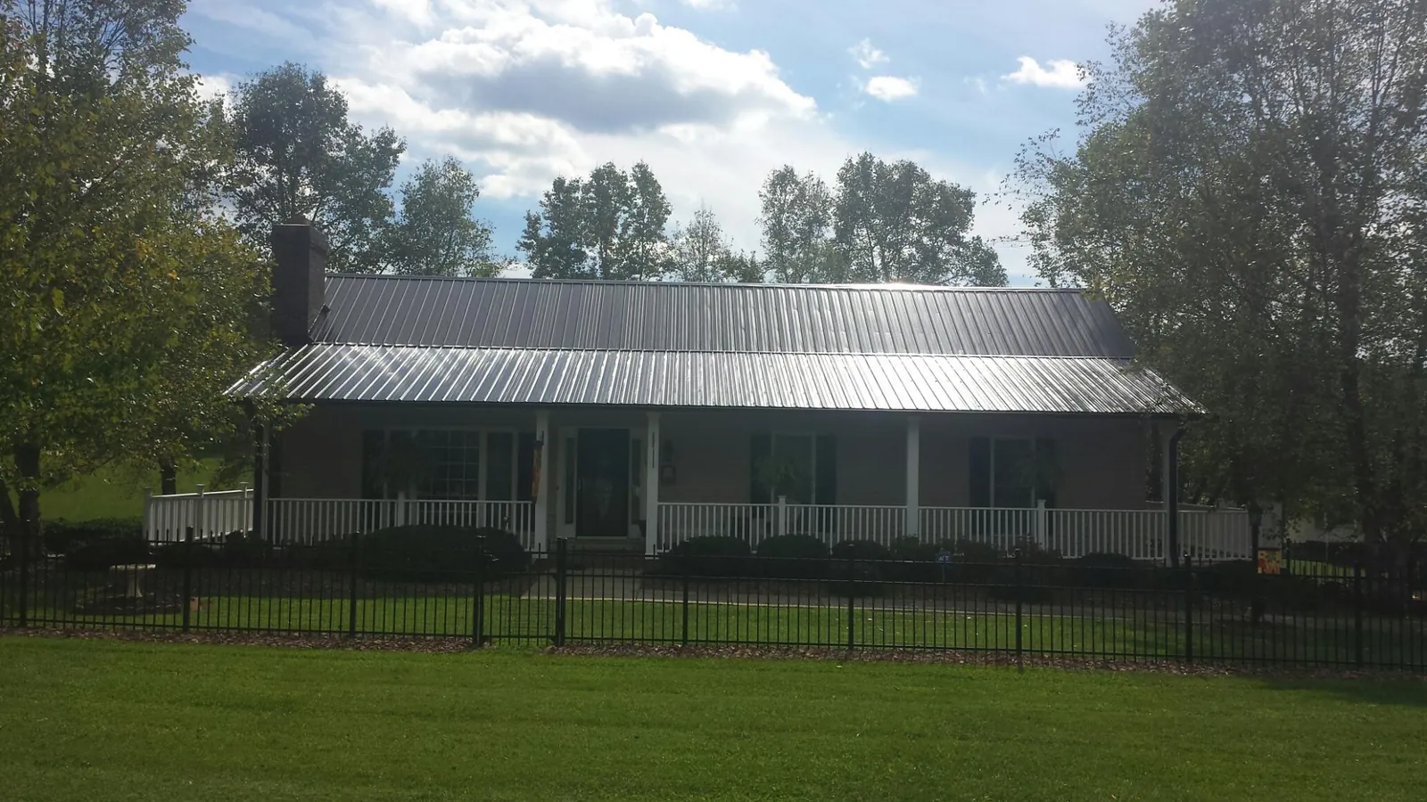 Gray metal roof on a brick ranch with a full width front porch — Gutter Guard Installation work by our crew in Candler